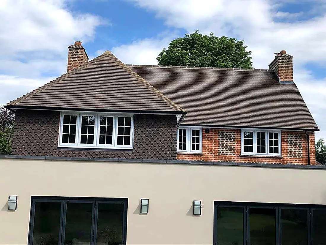 A finished Surrey house with a brown tiled hipped roof and rendered walls