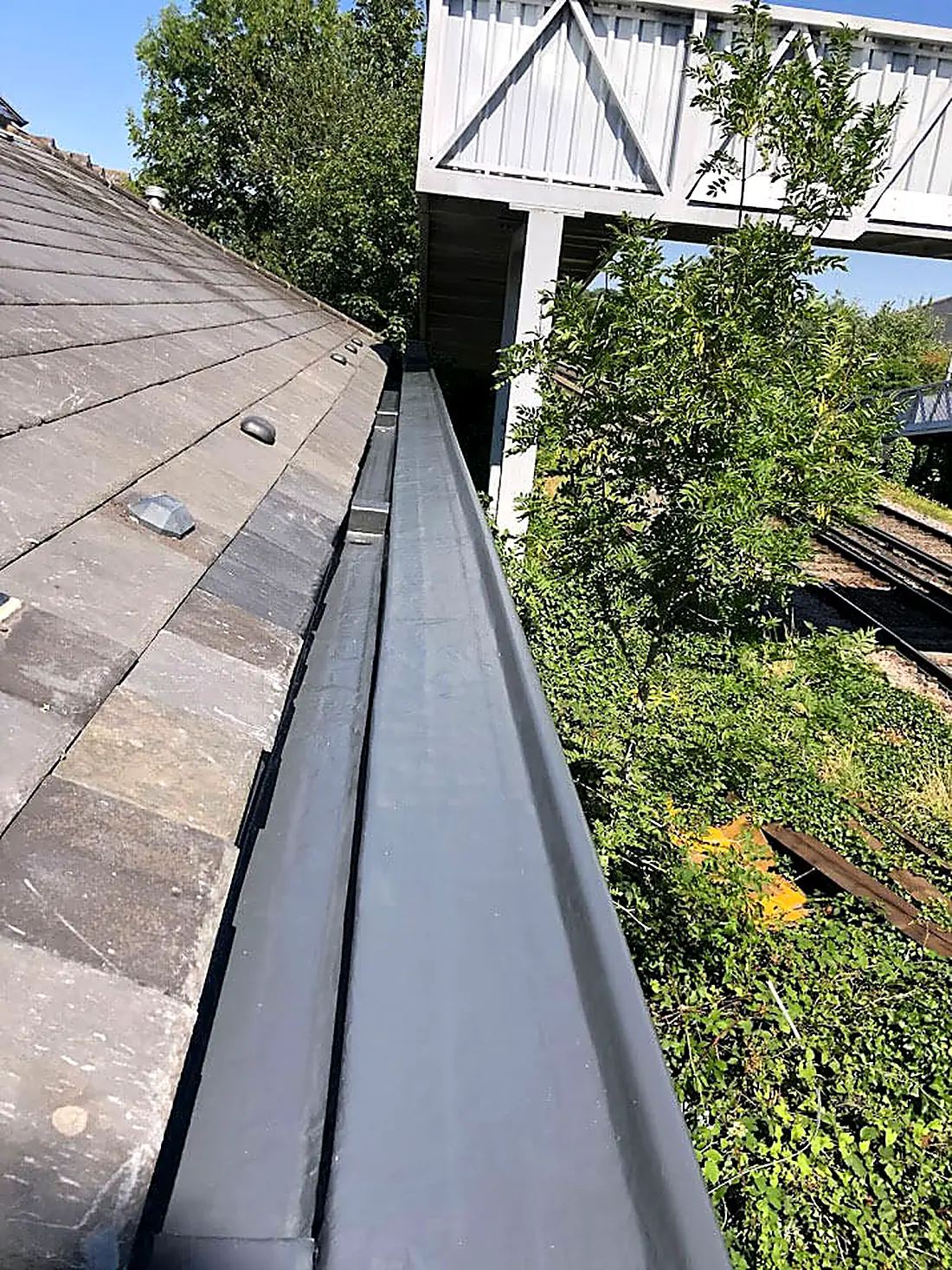 A lead lined valley gutter running between a tiled slope and a wall